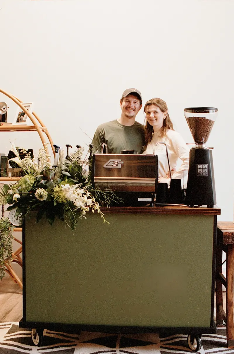 Kyle and Izzy behind the cart, florals across the bar top