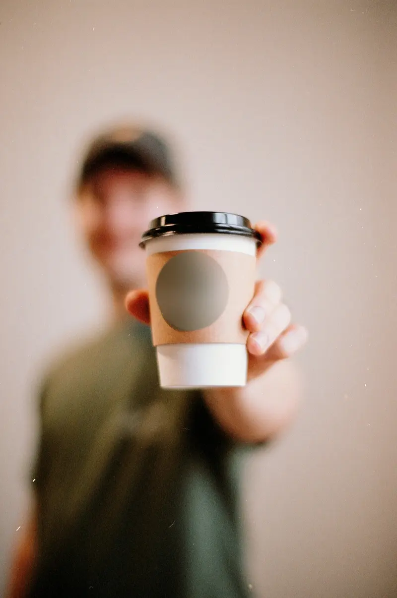 A to-go cup held out across the bar, shot on film