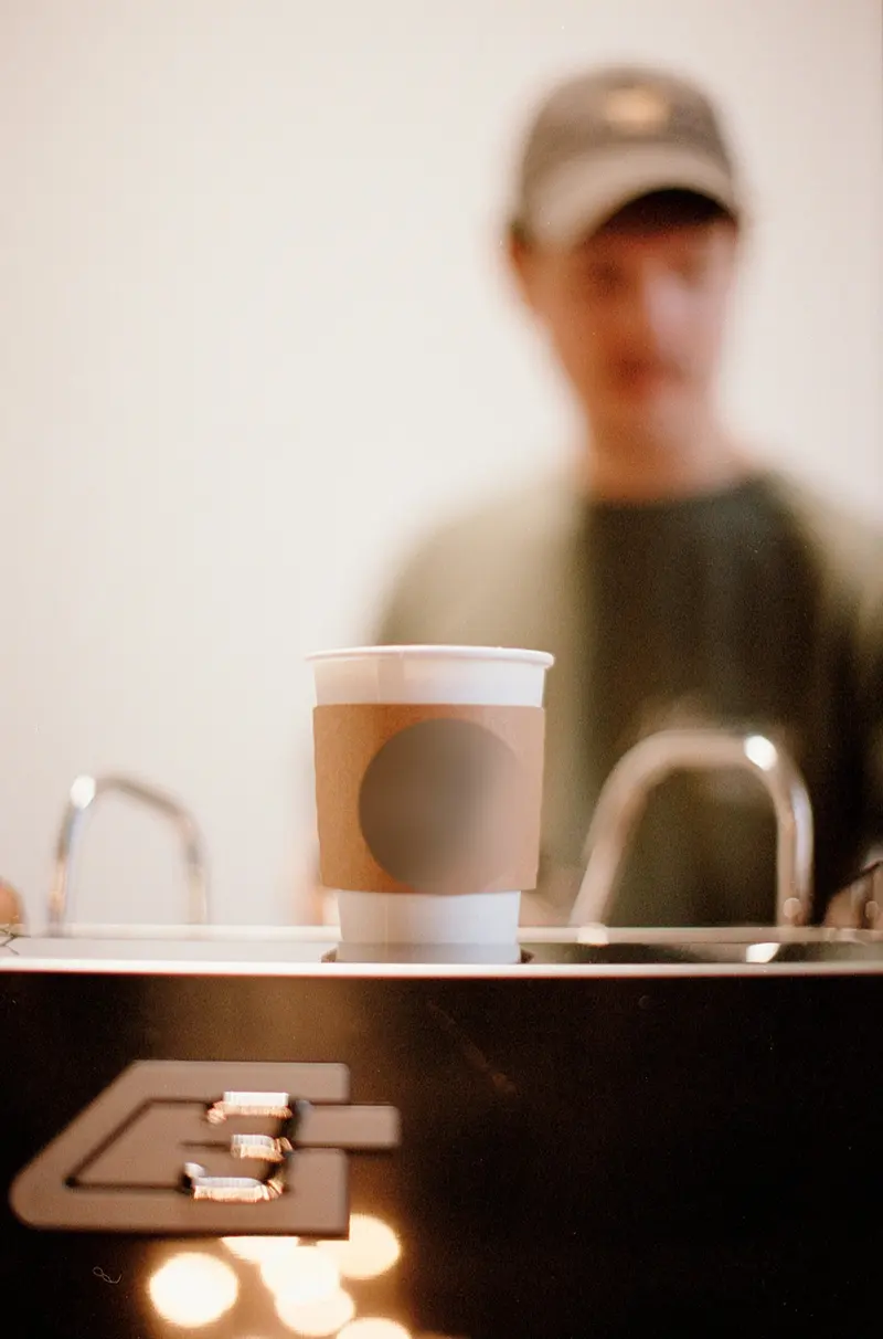 A finished drink in a kraft sleeve, resting on the bar